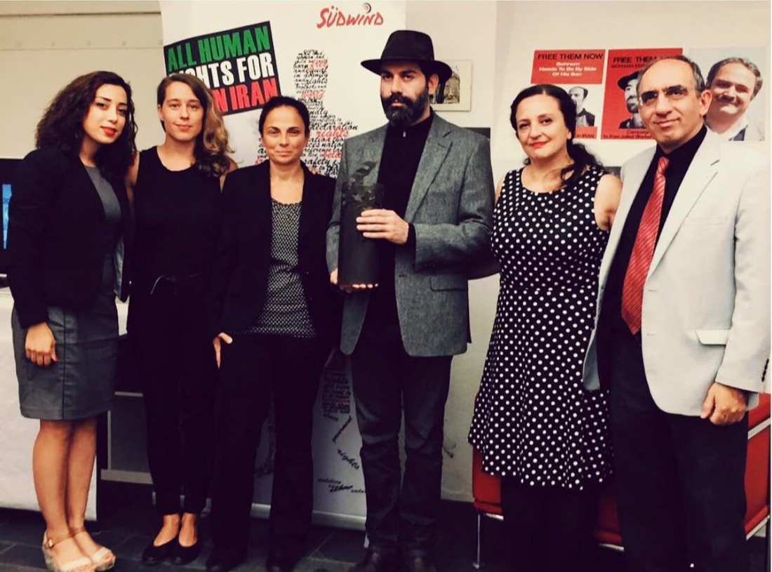 Parastoo Fatemi with the award jury and an award winner holding the Raha human rights award, in front of the All Human Rights for All in Iran banner