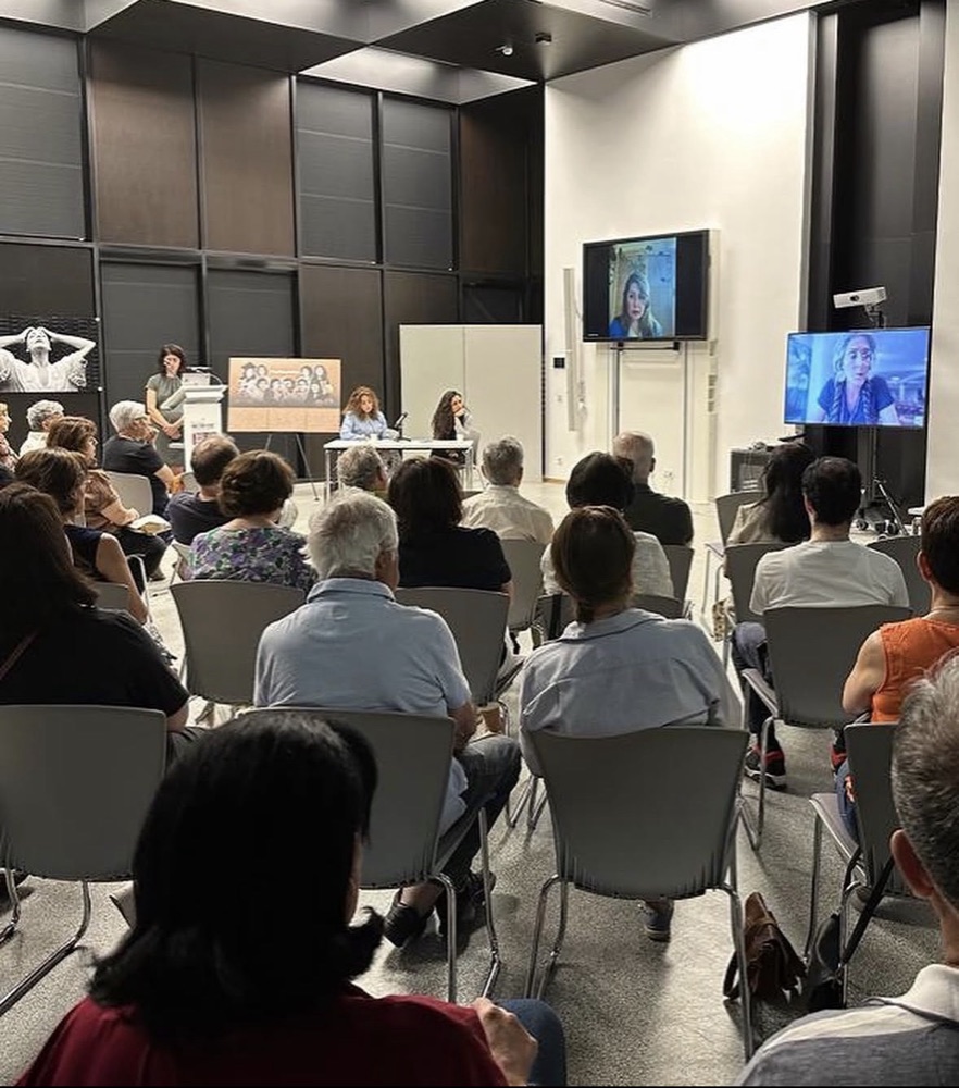 The event room at the University of Luxembourg, with a full audience and two speakers joining by video