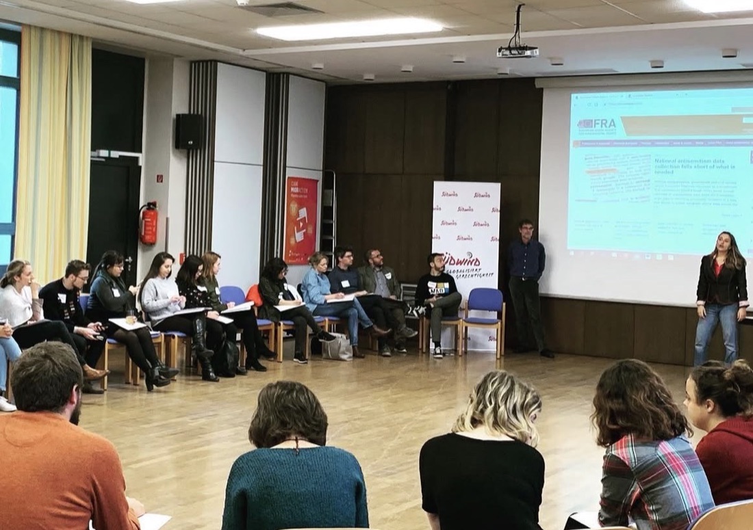 Journalists seated in a circle during a workshop at Südwind, with the EU Agency for Fundamental Rights website on the screen